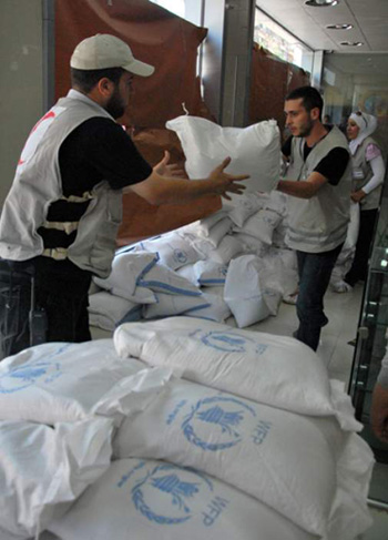 Nhân viên Chữ thập Đỏ Syria phân phát lương thực cho người dân Syria đi lánh nạn.